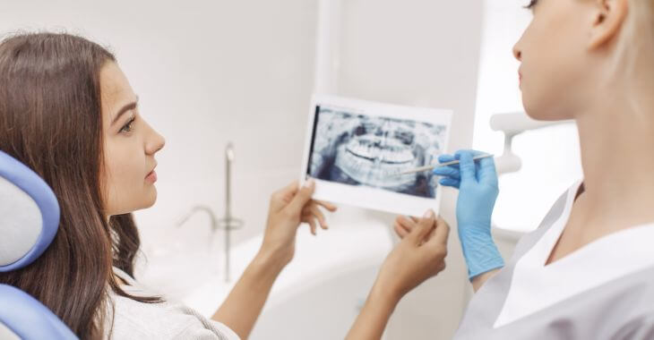 A dentist showing dental imaging to a female patient and explaining the issue