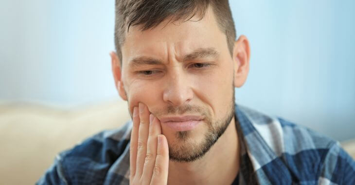 A concerned man pressing his cheek and jaw