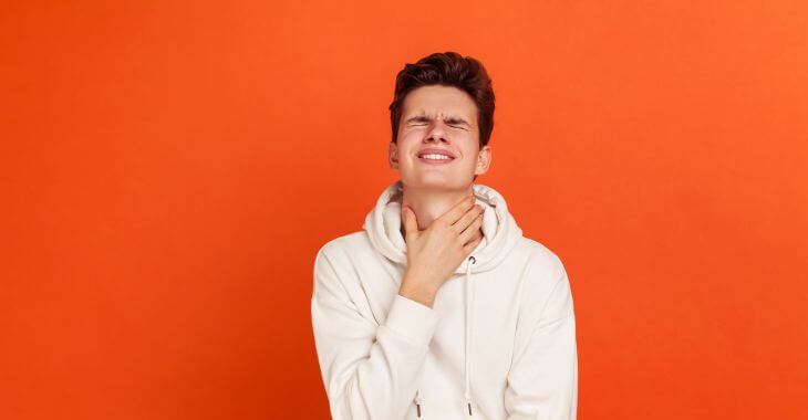 A stressed teenage boy touching his neck while swallowing