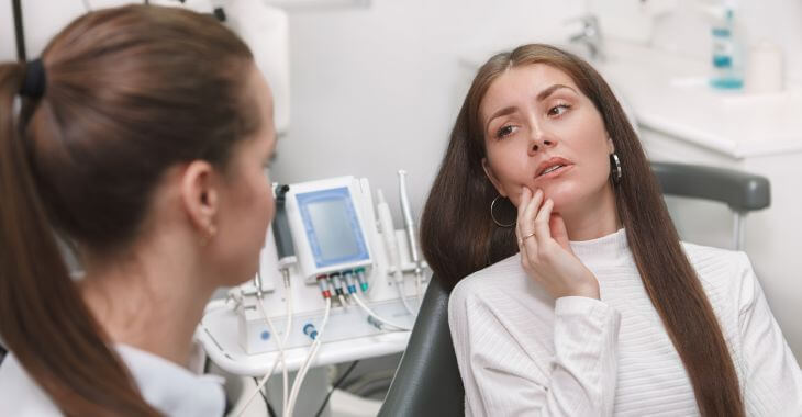 A dentist consulting a woman complaining about bone spur in mouth after tooth extraction.