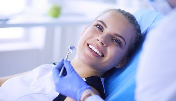 A happy woman with dental veneers after a routine dental checkup